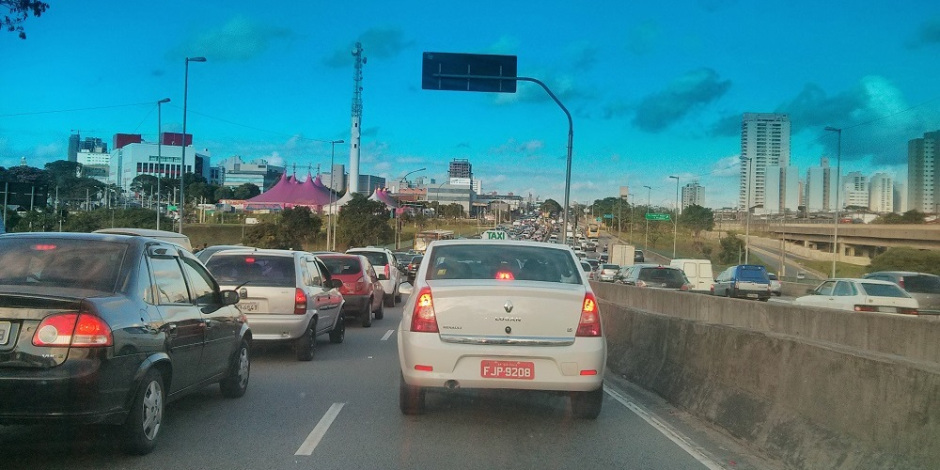 Imagem ilustra a crônica Monstros no Trânsito. Na foto, carros em uma rodovia aparecem em fila e não se movem. O trânsito está congestionado. O dia começa em São Paulo.