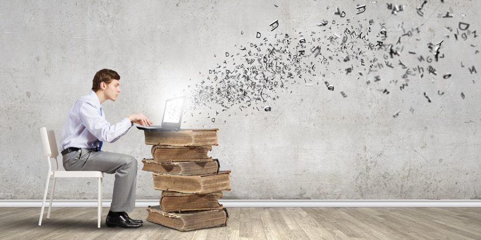 Homem sentado em uma cadeira no lado esquerdo da imagem escreve em um computador que está posicionado sobre uma pilha de livros antigos. A imagem dos livros foi ampliada para que passasse uma impressão de que eles são uma mesa e sustentam o notebook. Do notebook sai uma núvem com várias letras embaralhadas, simbolizando as ideias do homem e a sua escrita.