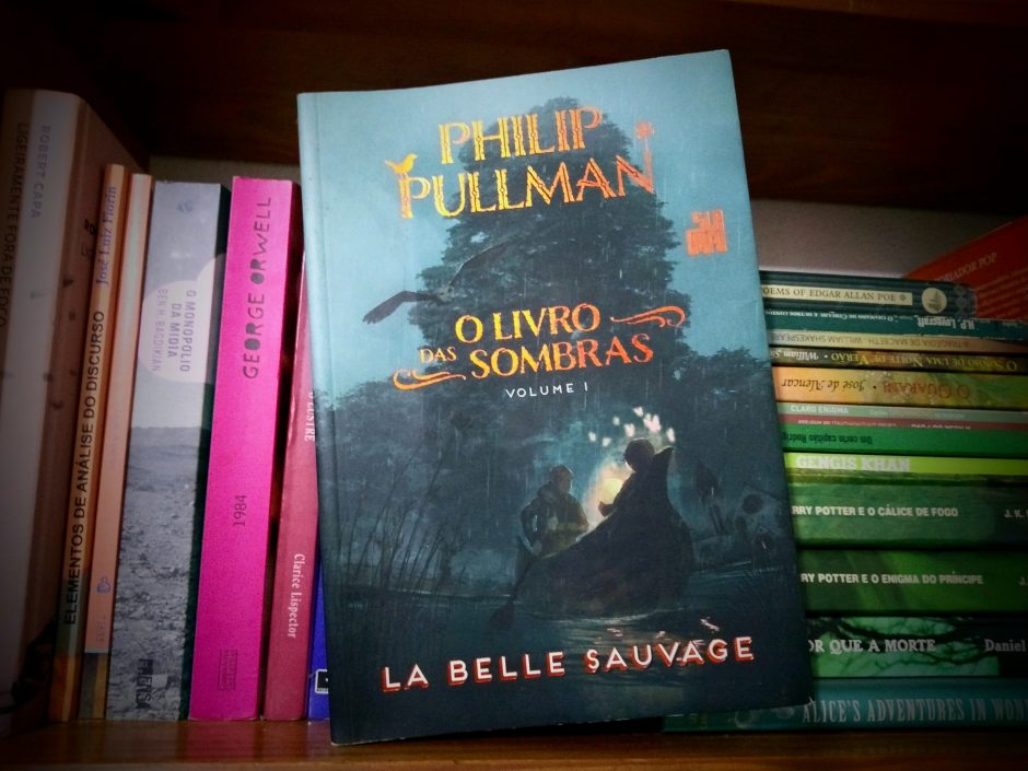 Livro la belle sauvage na estante na frente de outros livros