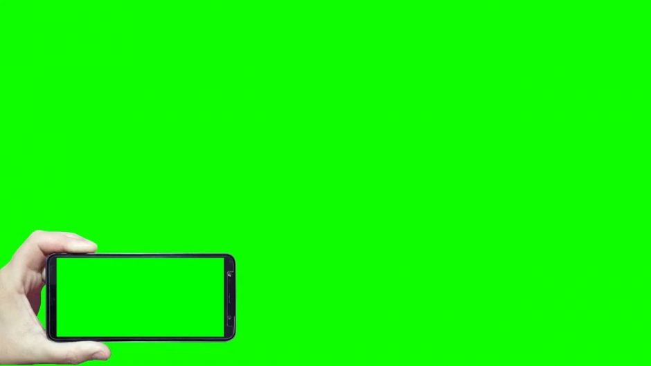 Uma mão segurando um celular filmando um fundo verde